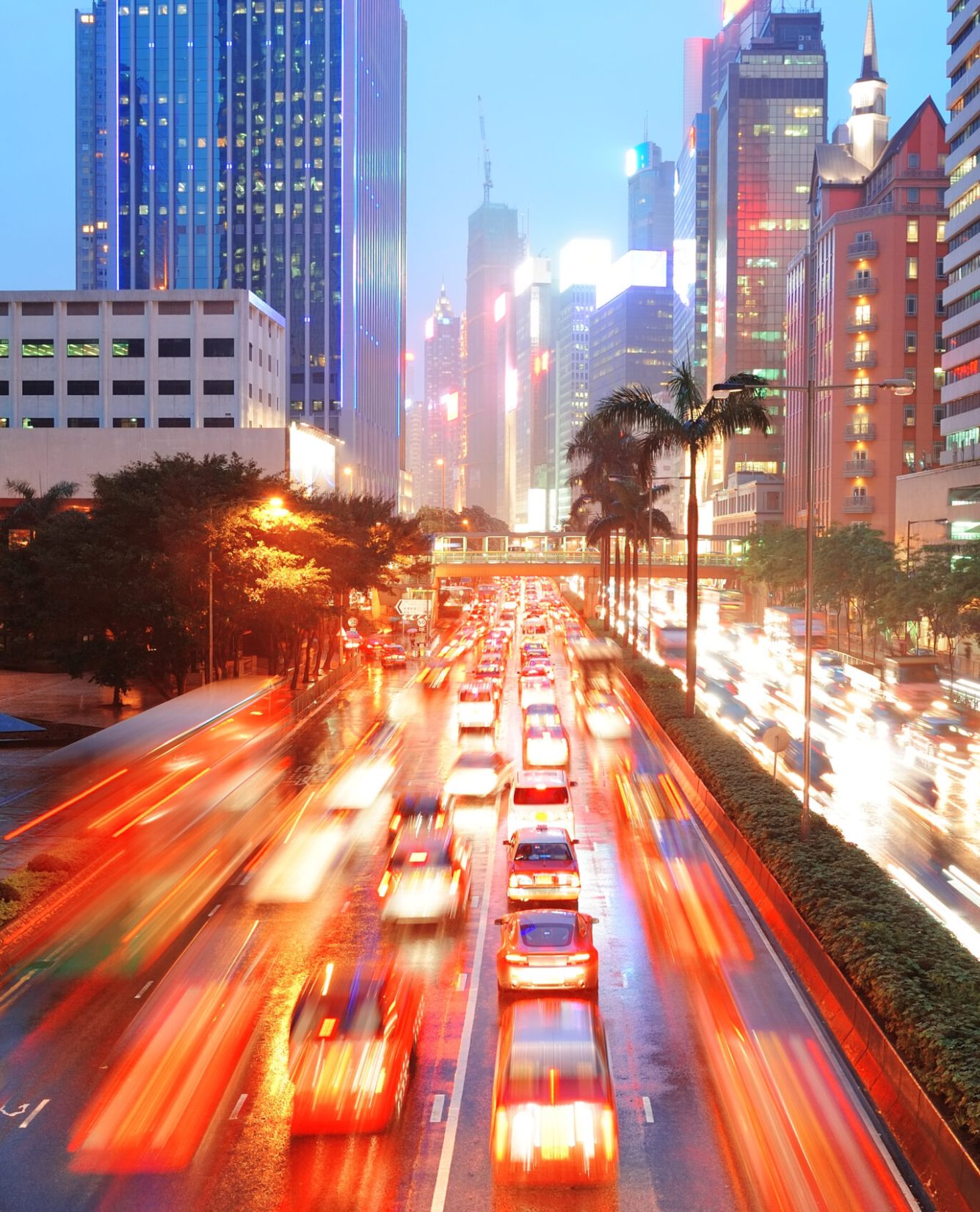 Hong Kong street with busy traffic and skyscraper office at dusk.